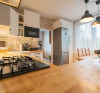 A kitchen in a 3-room apartment with brick cladding and a wooden decor floor.