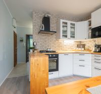 A kitchen with brick cladding and a wooden decor floor in a 3-room apartment.