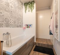 A bathroom in a 3-room apartment with decorative tiles and a wooden-patterned floor.