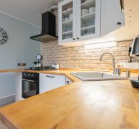 A kitchen in a 3-room apartment with brick cladding and a wooden decor floor.