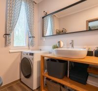Bathroom in a 3-room apartment with a sink, washing machine, mirror, and window with floral curtains.
