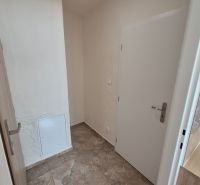 The entrance hall of a studio apartment with ceramic tiles and white walls, a simple interior.