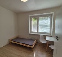 Studio apartment with a bed, table, and wooden floor decor, bright room.