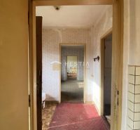 Hallway in a family house with an older carpet and a view of other rooms.