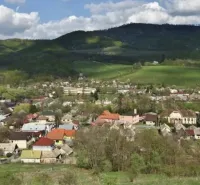 A view of Kokava nad Rimavicou surrounded by hilly landscape and gardens.