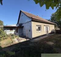 A family house in Tvrdošovce with a traditional roof and a garden surrounded by greenery.