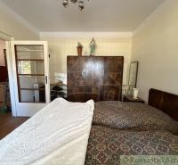 A bedroom in a family house with a large bed, a wardrobe, and white doors.