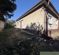 A family house in Tvrdošovce with a grassy plot and a side entrance gate.