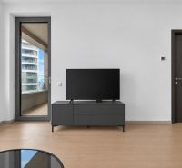 Living room in a two-room apartment with a wooden decor floor and a television.