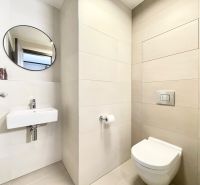 Bathroom in a 2-room apartment with a sink, toilet, and round mirror.