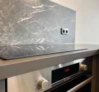 A kitchen unit in a 2-room apartment with an electric oven and marble decor.