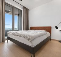 Bedroom with a large window, bed, and lamp in a 2-room apartment.