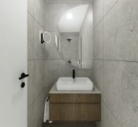 A bathroom with gray tiles and a sink in a 2-room apartment.
