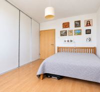 A bedroom with a wooden decor floor and paintings in a three-room apartment.