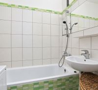 A bathroom with a bathtub, a sink, and green tiles in a 3-room apartment.
