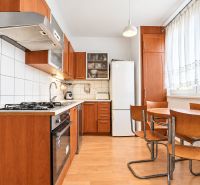A kitchen in a 3-room apartment with a wooden decor floor, a kitchenette, and a dining table.