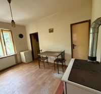 A kitchen in a family house with a wooden decor floor, a table, and a stove.