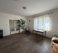A room in a family house with a large window, a table, and a floor with a wooden decor.
