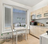 Office kitchenette with a dining table, large window, and wood-patterned floor.