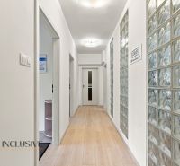 A narrow hallway in offices with a wooden decor floor and a glass wall.