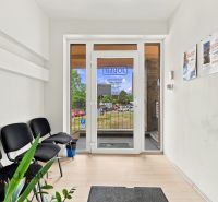 Entrance to offices with wood-patterned flooring, waiting area, and posters on the wall.