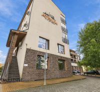 A building with a sign in Dunajská Streda. A parking lot and a tree surround the offices.