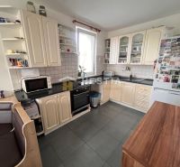A kitchen with a corner unit, white cabinets, and a black countertop in a three-room apartment.