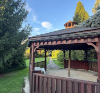 A garden gazebo by a family house in Trenčianske Stankovce surrounded by coniferous trees.
