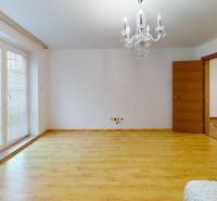 Interior of a family house with a chandelier, balcony doors, and a wooden decor floor.