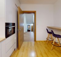 A kitchen in a family house with a wooden decor floor and bar seating.
