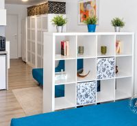 Compact interior of a one-room apartment with a wooden decor floor and modular furniture.