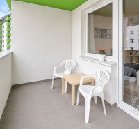 The balcony of a one-room apartment on Rustaveliho Street in Bratislava - Rača with two chairs.