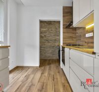 A kitchen with a wooden decor floor, white cabinets, and stone wall cladding.