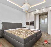 A bedroom with wood-patterned flooring, a built-in wardrobe, and lighting in a five or more room apartment.