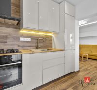 A kitchen in a 5 or more room apartment with a wooden decor floor and a light kitchen unit.