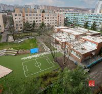 A view of the schoolyard with a playground and residential blocks on Donnerova Street in Karlova Ves.