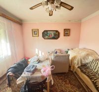 Living room in a family house with a couch, table, and paintings on the walls.