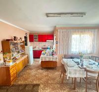 Dining room and kitchen in a family house with a red kitchen unit and a glass cabinet.