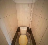 A toilet with beige tiles in a family house.