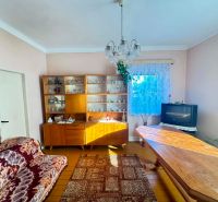 A living room in a family house with a wooden decor floor, carpets, and a television.