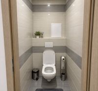 Bathroom in a 3-room apartment with a white toilet and gray tiles.
