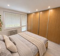 Bedroom in a 3-room apartment with a large wardrobe and bed, floor with wooden decor.
