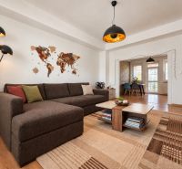 Living room with a sofa, a world map on the wall, and a floor with a wooden decor.