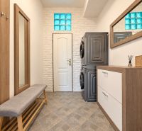 A hallway with a mirror, a washing machine, and a dryer in a 3-room apartment with a wooden decor floor.