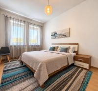 A bedroom in a 3-room apartment with a bed, an armchair, and a floor with a wooden decor.