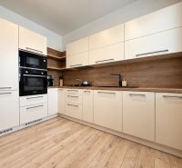 A kitchen in a 3-room apartment with light cabinets and a wood-patterned floor.