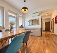 Dining room in a 3-room apartment with wood-patterned flooring and stylish lighting.