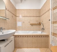 A bathroom in a 3-room apartment with a bathtub, sink, and tiles in soft tones.