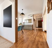 Interior with wood-patterned flooring, showing an entrance hallway and dining area in a 3-room apartment.