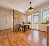 Living room in a three-room apartment with a wooden decor floor and a dining area.